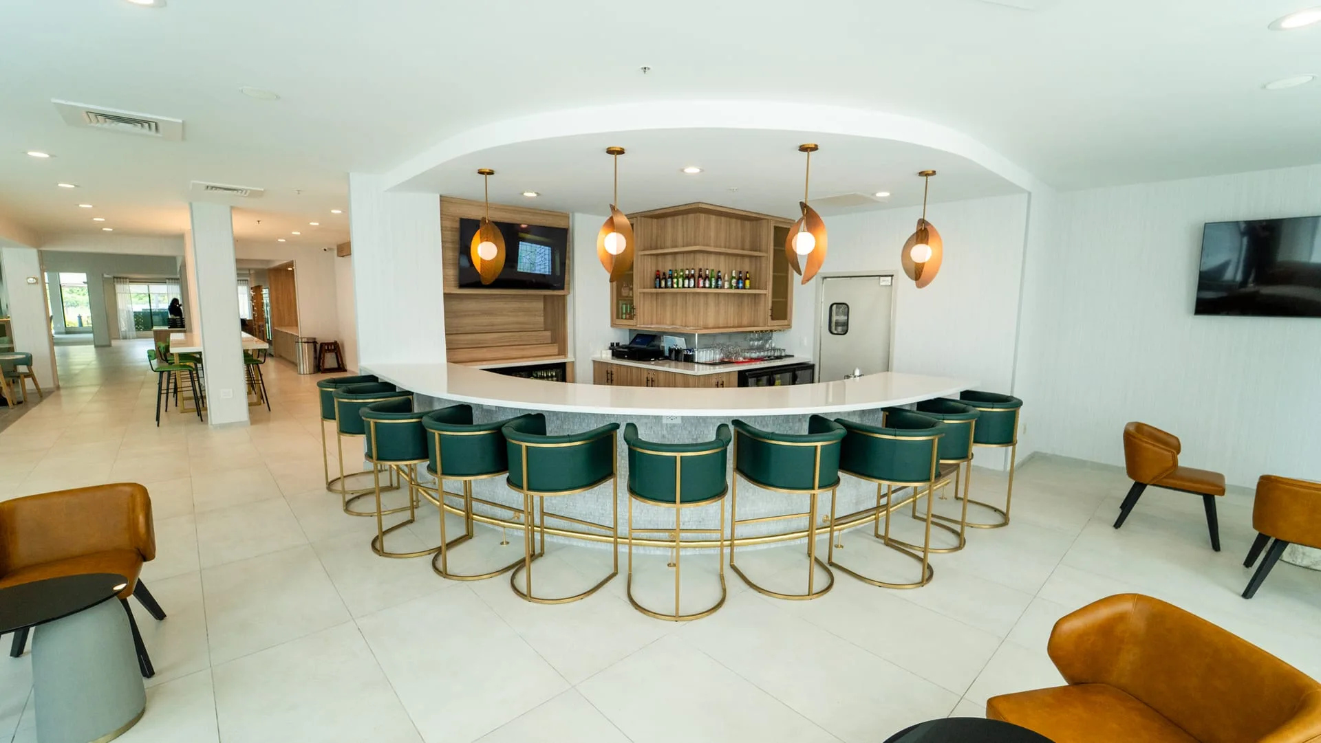 Hotel bar with a curved white countertop, green stools and open wood-look shelving behind